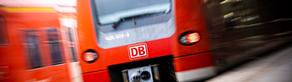 Eine rote Regionalbahn der Deutschen Bahn fährt in einen Bahnhof ein, vom Bahnsteig aus fotografiert.