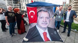 Deutsch-Türkische Wahlberechtigte vor ihrem Wahllokal in München mit einem überlebensgroßen Plakat von Erdogan