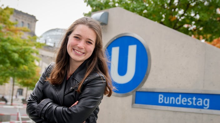Die mit 24 Jahren jüngste Abgeordnete Emilia Fester von Bündnis 90/Die Grünen sitzt vor dem Reichstagsgebäude auf der Mauer der U-Bahnstation Bundestag