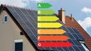 Über einem Haus mit Solarpanels auf dem Dach liegt eine Grafik, die die verschiedenen Klassen der Energieeffizienz in verschiedenen Farben darstellt.