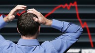 Börsenmakler vor einer Anzeigetafel die einen Börsencrash zeigt fasst sich an den Kopf Wirtschaft 