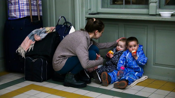 Eine Mutter mit Kindern ruht sich in einem provisorischen Unterstand in einem Bahnhofsgebäude aus, nachdem sie mit dem Zug nach Polen gekommen ist.
