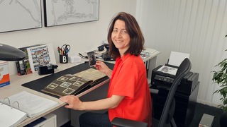 Birgit Düker bastelt an einem Schreibtisch an einem Fotoalbum.
