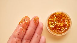 Finger mit goldendem Glitter aus einem Töpfchen