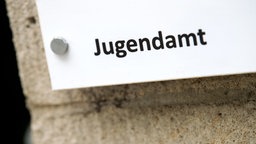 Ein weßes Schild an einer Mauer mit der Aufschrift "Jugendamt".