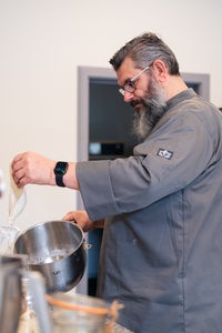 Ein bärtiger Mann arbeitet in einer Küche mit Sauerteig.