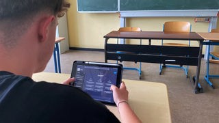 Ein Schüler hält ein Tablet in der Hand auf dem die KI Chat GPT geöffnet ist.