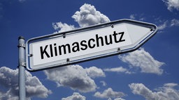 Auf einem Wegweiser befindet sich der Schriftzug Klimaschutz.