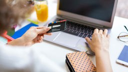Frau bei Online-Zahlung mit Kreditkarte vor Notebook.