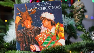 Das Cover der Schallplatte "Last Christmas" von Wham! liegt in einem Tannenbaum.