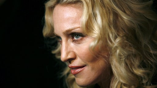 Madonna blickt nach oben in einer seitlichen Nahaufnahme vor schwarzem Hintergrund.