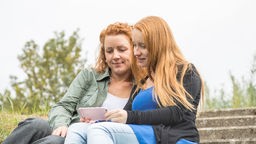 Zwei Frauen unterhalten sich, die eine zeigt der anderen ein Bild auf ihrem Smartphone