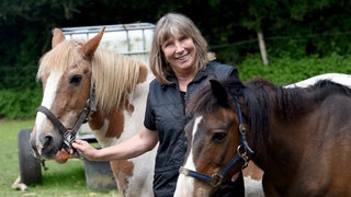 Petra Teegen steht in Norderbrarup (Schleswig-Holstein) auf einer Wiese ihrer "Pferdeklappe" zwischen den Ponys Pirat (30,l) und Herr Schröder (17)