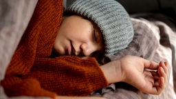 Symbolbild Long/Post-Covid: Ein Jugendlicher schläft in einem Bett