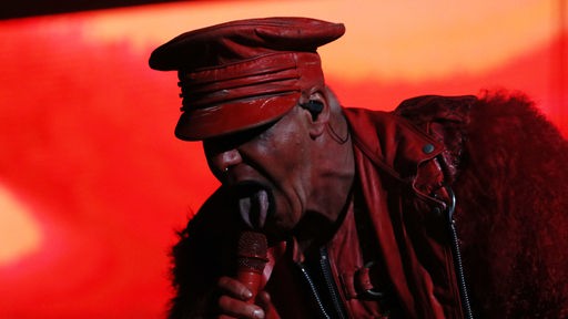 Till Lindemann, Sänger der Band Rammstein, auf der Bühne in rotem Kostüm