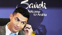 Christiano Ronaldo steckt sich bei einer Pressekonferenzt in Saudi-Arabien einen Kopfhörer ins Ohr.
