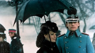 Filmszene aus Ludwig II.: Ludwig II. (Helmut Berger) und Elisabeth von Österreich (Romy Schneider) stehten im Schnee.