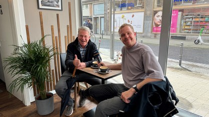 Carsten Sostmeier und Daniel Schlipf sitzen für ein Interview zusammen in einem Café.