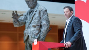 SPD-Vorsitzender Lars Klingbeil SPD steht an einem Rednerpult – im Hintergrund ist eine Statue von Willy Brandt zu sehen.