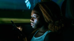 Eine junge Frau nutzt ein Smartphone in der Nacht