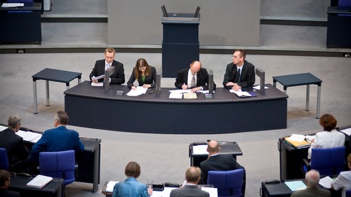 Vier Stenograf:innen sitzen im Plenum des Bundestags und schreiben mit.