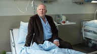 Eine Szene aus "Tatort: Borowski und die große Wut": Klaus Borowski (Axel Milberg) sitzt nachdenklich auf einem Krankenhausbett