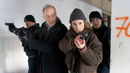 Szene aus dem Tatort "Unter Feuer": Peter Schnabel (Martin Brambach), Karin Gorniak (Karin Hanczewski) und Polizisten mit vorgehaltenen Pistolen