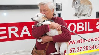 Eine Frau mit Hund steht vor dem mobilen Tierarzt in Bonn