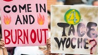 Schildern mit der Aufschrift "Come in and Burnout" und "4 Tage Woche?" bei einer Demonstration von Ärzten in Berlin.