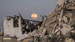 Der Vollmond geht am frühen Abend über zerstörten Gebäude im Zentrum des Gazastreifens auf.