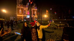 Menschen mit Weihnachtsmützen machen Seldies vor der weihnachtlich geschmückte Kathedrale in Neu-Delhi