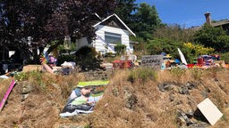 Ein "Yard Sale" in Kanada: Vor einem kleinen Häuschen liegen auf einer Wiese Dinge, die verkauft werden sollen