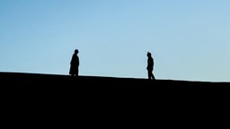 Schatten einer Frau und eines Mannes am Horizont, die sich im Streit gegenüber stehen 