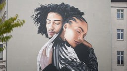 Wandbild auf einem Haus; zwei Menschen umarmen sich