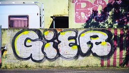 Graffiti-Schriftzug "Gier" auf einer Mauer