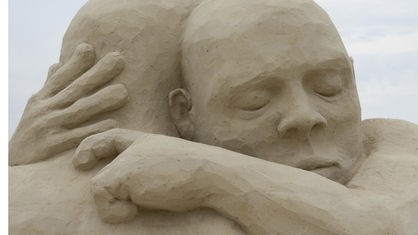 Eine Sandskulptur zwei sich umarmender Menschen