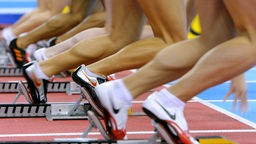 Die Beine von Läufern in Startmaschinen auf einer Tartan-Bahn