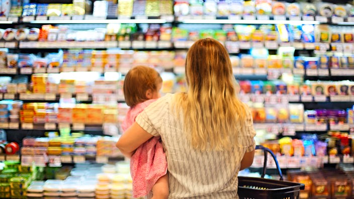 Mutter steht mit ihrer Tochter vor Supermarktregalen