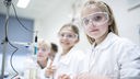 Schüler:innen mit Schutzbrillen experimentieren im Chemie-Unterricht