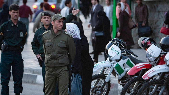 Eine Gruppe von Sittenpolizisten steht in grünen Uniformen am Straßenrand. Rechts von Ihnen stehen Motorräder mit der Aufschrift "Police"