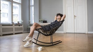 Eine junge Frau entspannt auf einem Schaukelstuhl