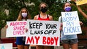  Frauen, die für das Recht auf Abtreibung demonstrieren, halten Plakate während einer Kundgebung vor dem Gerichtsgebäude von Columbia County