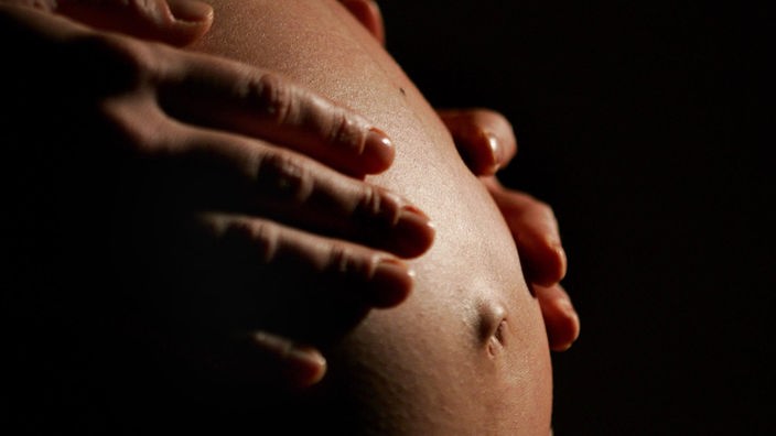 Eine Schwangere hält ihre Hände an ihren Bauch