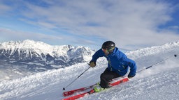 Ein junger Skifahrer mit sportlichen Fahrstil bei der Abfahrt