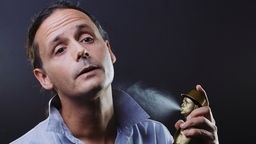 Kabarettist Philipp Weber riecht an einem Stoß Parfum, welches er sich gerade ins Gesicht sprüht