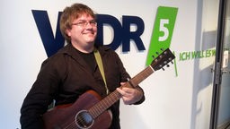 Kabarettist Matthias Reuter mit Gitarre im WDR 5-Studio