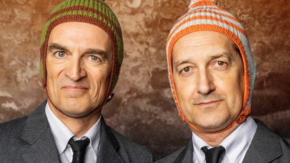 Foto: Enrico Meyer / Comedy-Duo Ulan und Bator mit Bommelmützen vor orangener Tapete