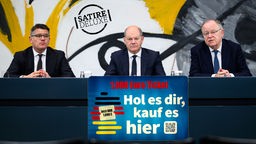 Olaf Scholz, Boris Rhein und Stephan Weil auf einem Podium, darunter ein Schild auf dem das neue 1000 Euro Ticket verkündet wird