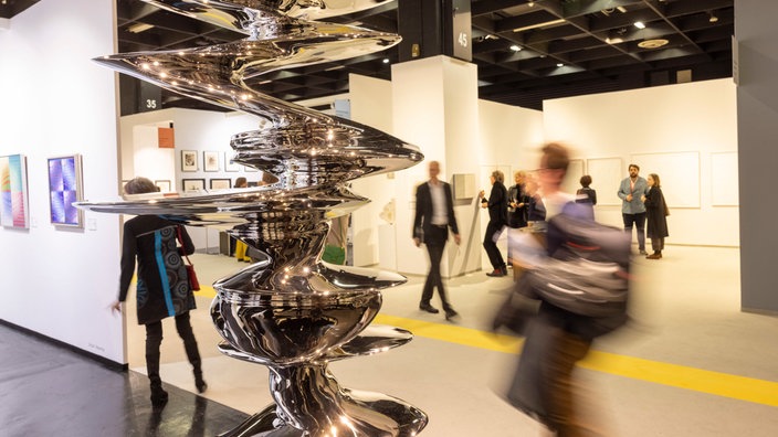 Besucher gehen auf der Art Cologne Kunstmesse an der Skulptur aus Edelstahl von Tony Cragg mit dem Titel "Elliptical Columna" vorbei.