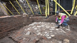 Eine Archäologin legt Mauer-Überreste eines alten Theaters in London frei.